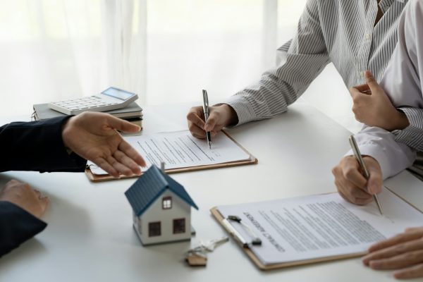 Real estate agent with couple closing a deal and signing a contract.